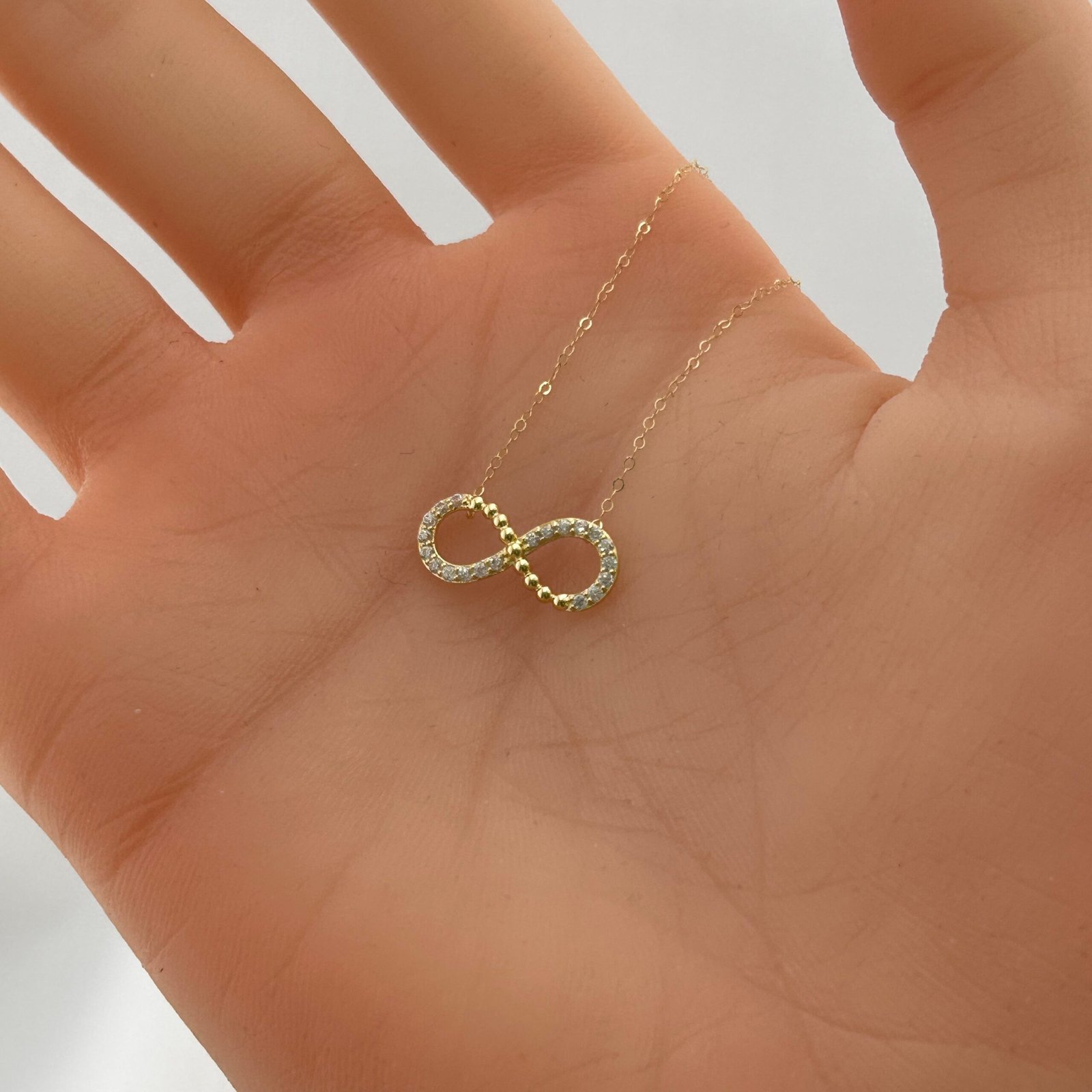 IMG_2828 تعليقة ذهب عيار 18 بشكل رمز اللانهاية مرصعة بفصوص براقة من جولدانا